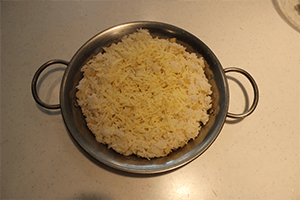 パエリヤ鍋（耐熱容器）にじゃがいもごはんを平らに入れ、上にミックスチーズを散らす。